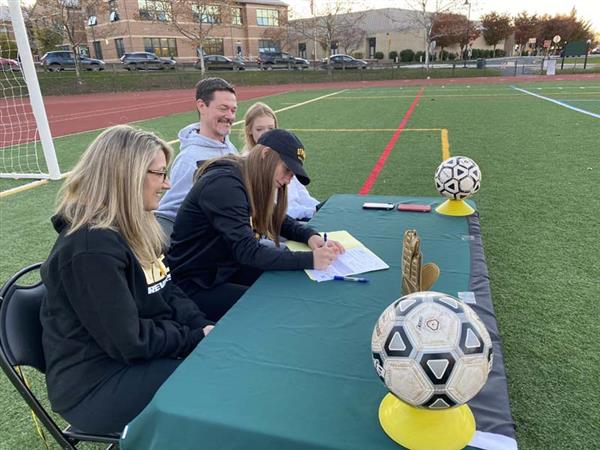 student signing letter at table set up on soccer field