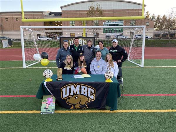 High School senior Sara Gavagan, Athletic Director John Buonamano and others taking group photo at table on soccer field
